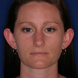 Person with long hair and earrings, neutral expression.