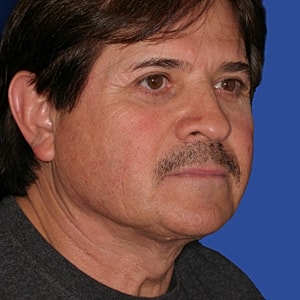 Man with mustache against blue background.