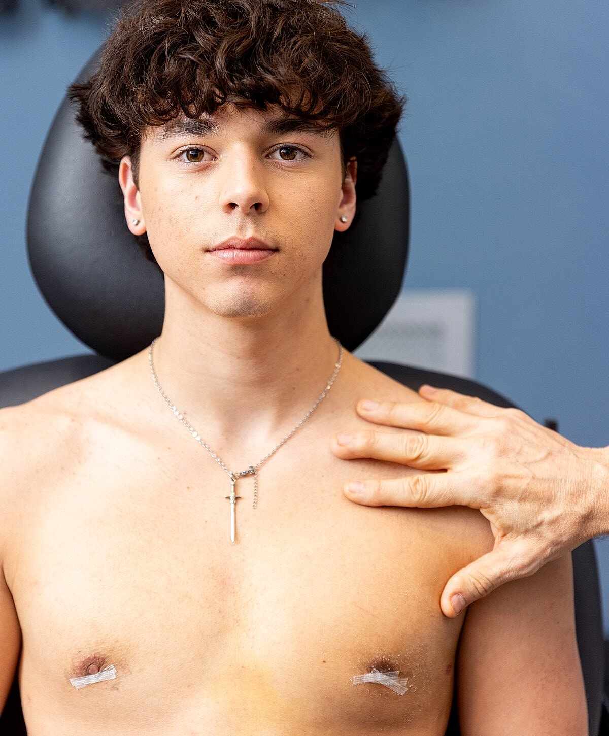 Young man in chair with hand on shoulder.