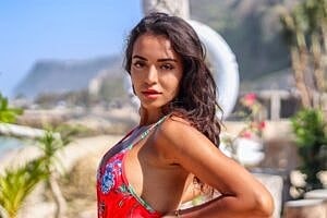 Woman in a floral swimsuit by the beach.