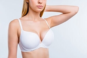 Model wearing a white bra against a plain background.