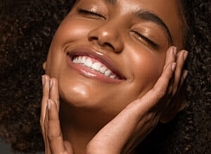 Smiling woman with curly hair and glowing skin.