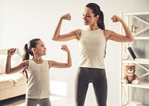 Mother and daughter flexing muscles together.