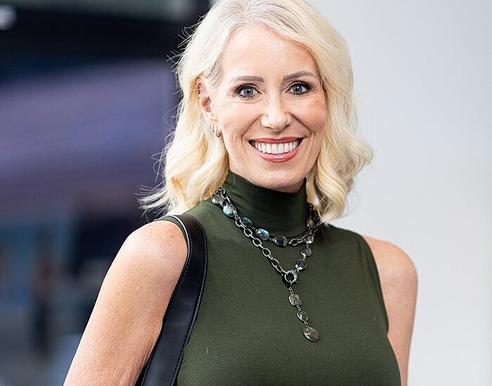 Smiling woman wearing green top and necklace.