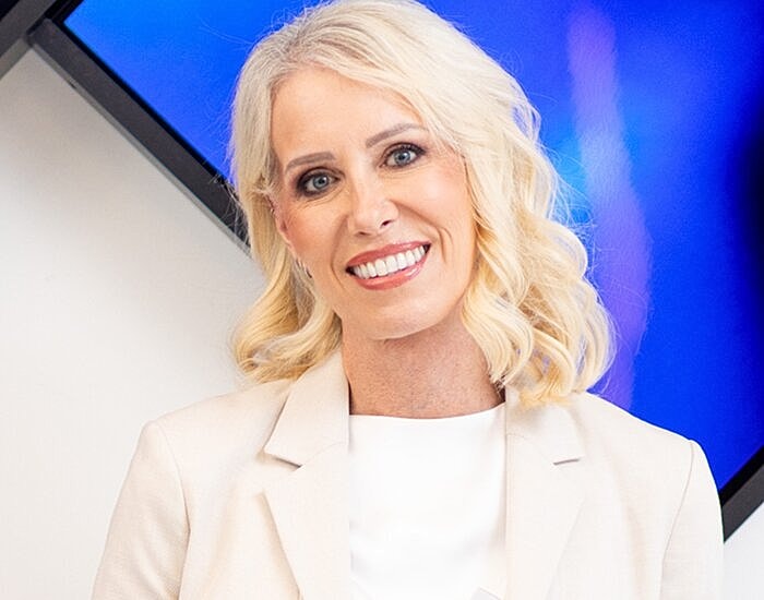 Smiling woman in a cream blazer.