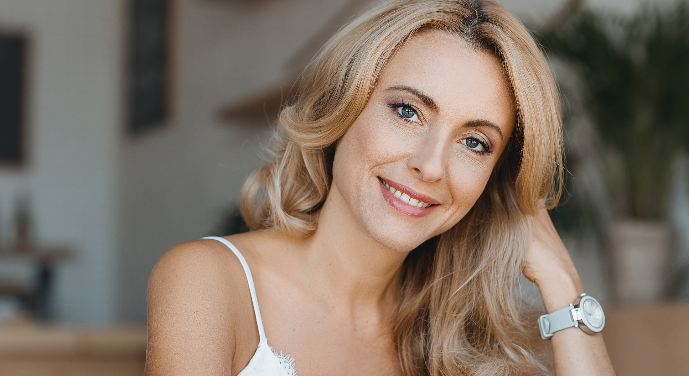 Smiling woman with blonde hair in casual setting.